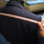 Master tailor taking bespoke garment measurements on dummy