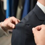 Professional tailor adjusting customer suit during fitting session