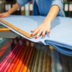 Woman measures the fabric in textile store
