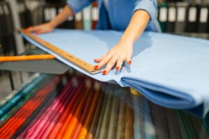 Woman measures the fabric in textile store